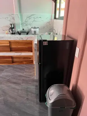 a kitchen with a black refrigerator and a trash can at Paquera apartment in Paquera