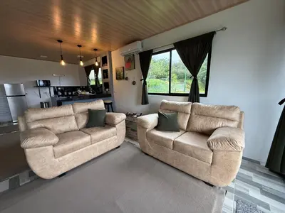 a living room with two chairs and a kitchen at Arenal cautiva in El Castillo de La Fortuna