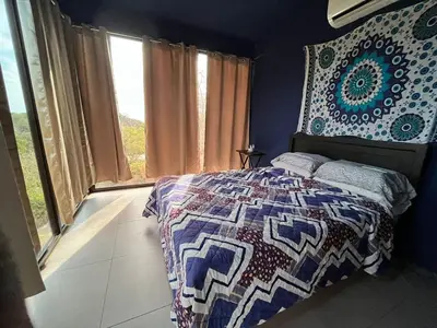 a bedroom with a bed and a large window at Golden Sunset Loft in Tamarindo