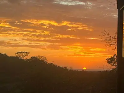 a sunset with the sun setting in the horizon at Golden Sunset Loft in Tamarindo