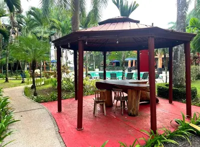 a gazebo with a table and chairs on a red floor at Walk-out Beachfront Condo - Surfer's Paradise in Playa Hermosa