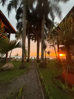 a resort with palm trees and the ocean at sunset at Walk-out Beachfront Condo - Surfer's Paradise in Playa Hermosa