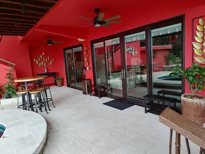 a patio with a red wall and tables and chairs at Villa Jardin in Quepos