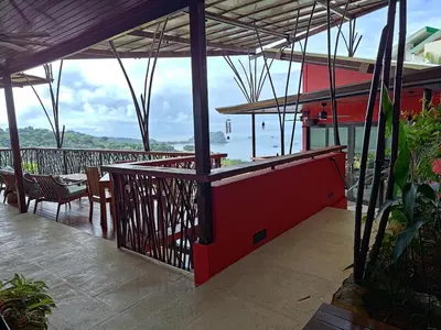 a patio with a table and chairs and a view of the water at Villa Jardin in Quepos