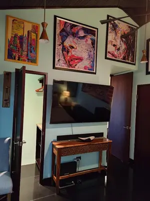 a living room with a table and a tv on a wall at Villa Jardin in Quepos