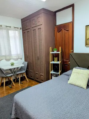 a bedroom with a bed and a desk and a chair at Habitación Sabana in San José