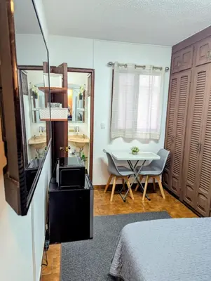 a room with a bed and a table and a television at Habitación Sabana in San José