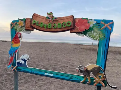 a sign on the beach with a monkey and a parrot at CL127 Modern Penthouse in Jacó