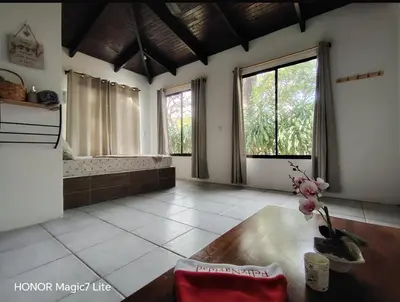 a living room with a table and some windows at Green Point Nature Retreat in Nosara
