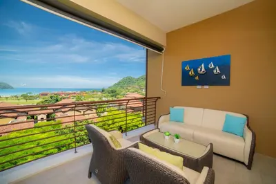 a balcony with a couch and chairs and a large window at Miramar 2D -3 bedr 3 bath Ocean View in Herradura