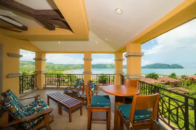a balcony with chairs and tables and a view of the water at Marbella 2A 3 BR in La Mona