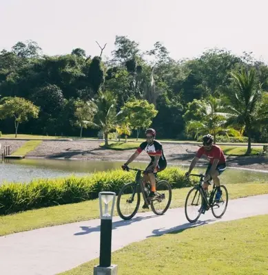 two men riding bikes on a path near a pond at Beach Apartment with Pool and Lake - Playa Hermosa in Muñeco