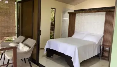 a bedroom with a bed and a chair and a window at La Casita El Perezoso in San Rafael
