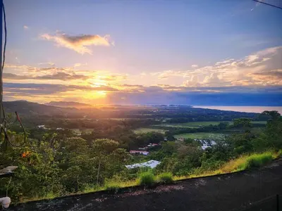 a view of a sunset from a hill with trees at Casa Pura Vista in Playa Hermosa