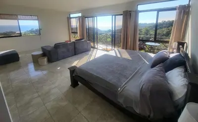 a bedroom with a bed and a couch and windows at Casa Pura Vista in Playa Hermosa