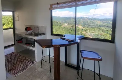 a kitchen with a table and two stools and a window at Casa Pura Vista in Playa Hermosa