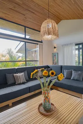 a living room with a blue couch and a vase with flowers at Villa Bernard - luxurious home walking distance to the beach in Tamarindo