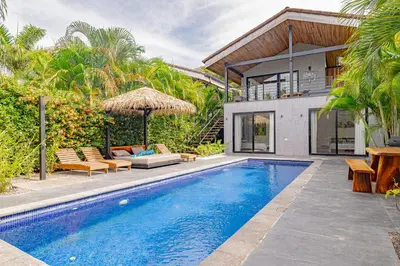 a villa with a swimming pool and a house at Villa Bernard - luxurious home walking distance to the beach in Tamarindo