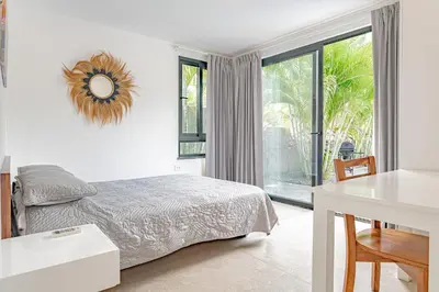 a bedroom with a bed and a table and a window at Villa Bernard - luxurious home walking distance to the beach in Tamarindo