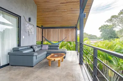 a living room with a couch and a table on a balcony at Villa Bernard - luxurious home walking distance to the beach in Tamarindo