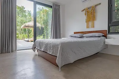 a bedroom with a bed and a large window at Villa Bernard - luxurious home walking distance to the beach in Tamarindo