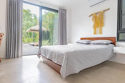 a bedroom with a bed and a large window at Villa Bernard - luxurious home walking distance to the beach in Tamarindo