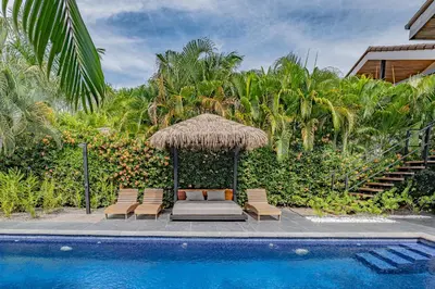 a bed and chairs next to a swimming pool at Villa Bernard - luxurious home walking distance to the beach in Tamarindo