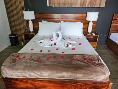 a bed with red rose petals on it at Villa Oropéndola Sarapiquí in Colonia Carvajal