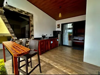 a living room with a wooden table and a television at Villa Oropéndola Sarapiquí in Colonia Carvajal