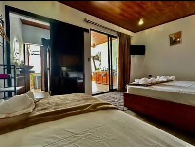 a bedroom with two beds and a balcony at Villa Oropéndola Sarapiquí in Colonia Carvajal