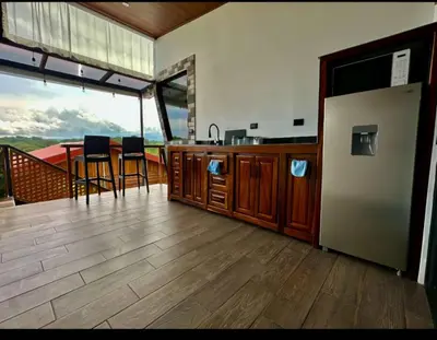 a kitchen and dining room with a view of the mountain at Villa Oropéndola Sarapiquí in Colonia Carvajal