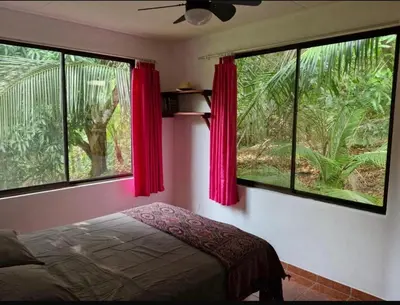 a bedroom with two large windows with red curtains at El Diamante - Colibri in Playa Hermosa