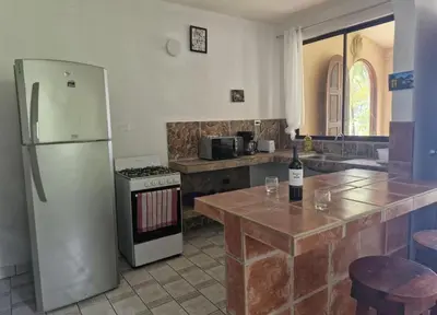 a kitchen with a refrigerator and a table with a bottle of wine at El Diamante - Colibri in Playa Hermosa