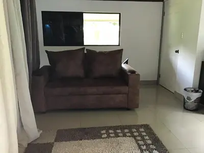 a brown couch in a living room with a window at Apartamento Paseo Damitas in Parrita