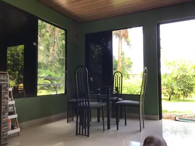 a dining room with a table and chairs and windows at Apartamento Paseo Damitas in Parrita