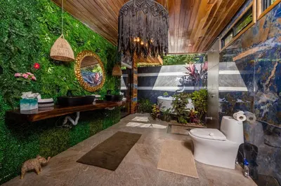 a bathroom with a green wall with plants at Ocho Artisan Bungalows in Tamarindo