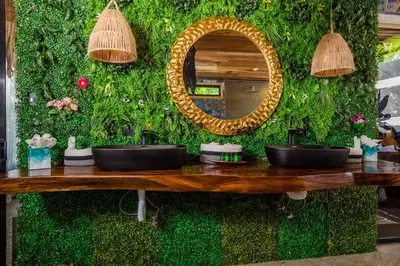 a green wall with two sinks and a mirror at Ocho Artisan Bungalows in Tamarindo
