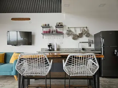a kitchen with two white chairs and a counter at Jardin De Poas Hotel & Nature Resort in Poás