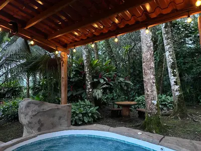 a swimming pool under a wooden pergola with a swimming pool at Cabin with private tropical forest in Tanque