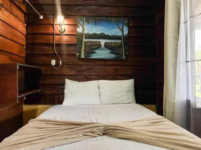 a bed in a room with wooden walls at Cabin with private tropical forest in Tanque