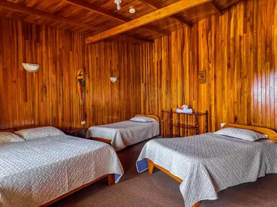 two beds in a room with wooden walls at Hotel El Atardecer in Monteverde Costa Rica
