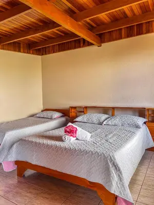 two beds in a room with wooden ceilings at Hotel El Atardecer in Monteverde Costa Rica