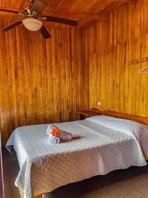 a bedroom with a bed with wooden walls and a ceiling at Hotel El Atardecer in Monteverde Costa Rica