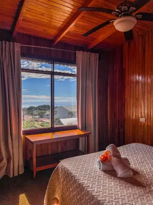 a bedroom with a bed and a large window at Hotel El Atardecer in Monteverde Costa Rica