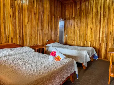 two beds in a room with wooden walls at Hotel El Atardecer in Monteverde Costa Rica