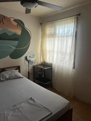 a bedroom with a bed and a window with a fan at Private Room One block from the beach in Coco