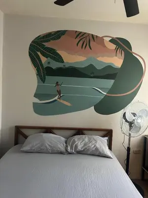 a person on a surfboard in a painting on the wall at Private Room One block from the beach in Coco