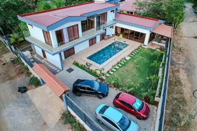 two cars parked in front of a house with a swimming pool at Casa Pura Vida in Coco