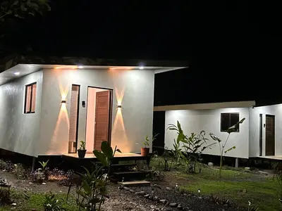 a small white house with a porch at night at Bungalows Chachagüita in Chachagua
