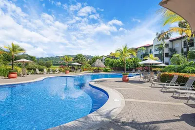 a swimming pool at a resort with chairs and umbrellas at Del Mar 5F 3 bedr 2 bath in Herradura